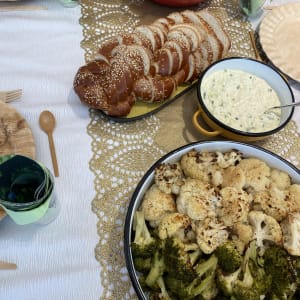 שולחן ערוך עם חלה, סלט, ירקות צלויים ורוטב