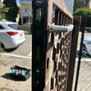 מנעול מותקן על שער מתכת עם תיק כלים ברקע