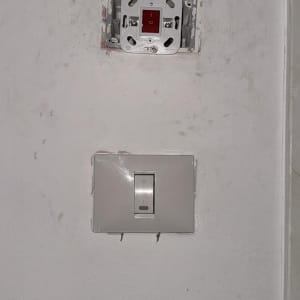 שקע חשמלי פתוח ומתג על קיר לבן