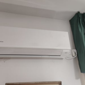 מזגן מותקן על קיר ליד וילון ירוק