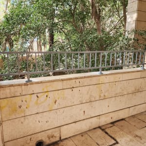 מעקה מתכת אפור על קיר אבן חיצוני