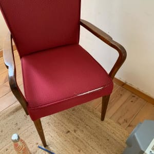 כיסא מרופד אדום עם קרע קטן בבד