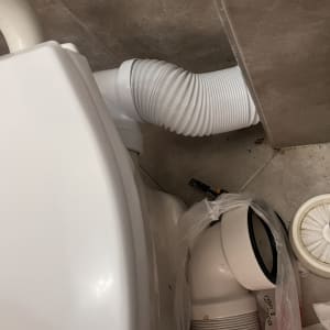 צינור גמיש לבן ליד אסלה וחלקי אינסטלציה