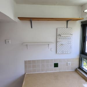 מדף עץ על קיר לבן עם לוח חורים