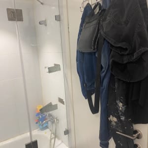 מקלחת עם דלת זכוכית ובגדים תלויים על הדלת