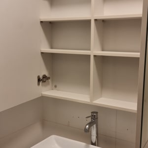 ארון פתוח עם מדפים מעל כיור וברז