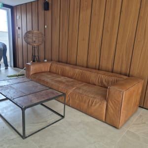 אדם מנקה רצפה ליד ספה חומה ושולחן מתכת