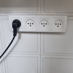 שקע חשמל עם תקע מחובר על קיר לבן