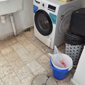 מכונת כביסה וציוד ביתי בפינת שירות בחצר