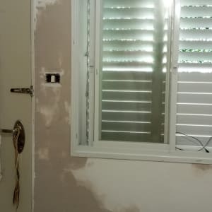 קיר עם תיקוני צבע וטיח ליד חלון ודלת