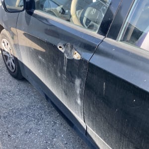 נזק לדלת רכב שחור עם סימני שפשוף