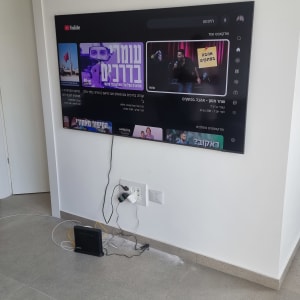 טלוויזיה מותקנת על הקיר עם כבלים ומודם על הרצפה