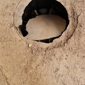 פתח ביוב עגול ברצפה עם נעליים לידו