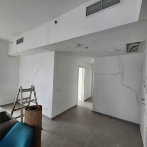 סולם עומד בחדר עם קירות לבנים וסימני תיקון