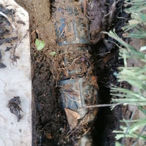 צינור חשוף באדמה עם לכלוך וענפים