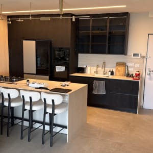 מטבח מודרני עם אי, כיסאות בר, כיור וברזים, תנור ומקרר.