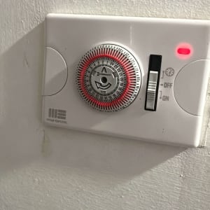 טיימר חשמלי מותקן על קיר עם נורית חיווי אדומה