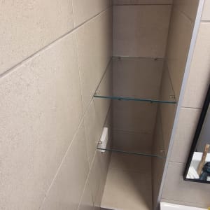 מדף זכוכית תלוי על קיר בחדר אמבטיה