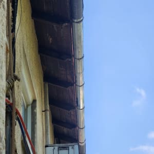 מרזב מתכת מחובר לגג עץ עם קורות חשופות