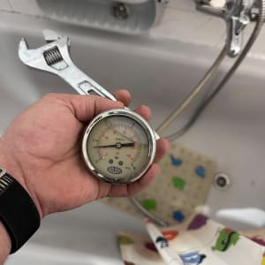 יד מחזיקה מד לחץ ליד אמבטיה