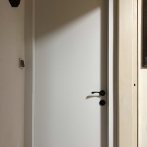 דלת לבנה עם ידית שחורה על קיר בהיר