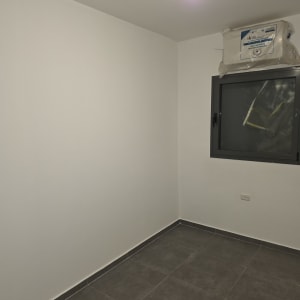 חדר צבוע עם קירות לבנים ורצפת אריחים אפורה