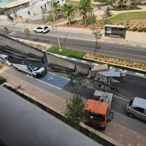 מנוף מעביר קופסה לרחוב עם מכוניות ואנשים