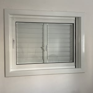 חלון אלומיניום עם תריסים סגורים על קיר לבן