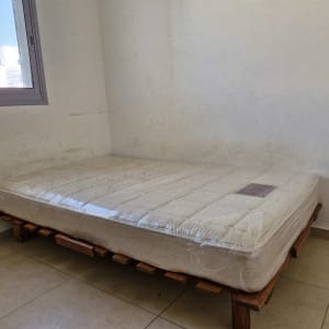 מזרן על בסיס עץ בחדר ריק עם חלון