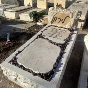 מצבה עם כיתוב בעברית ואבנים מסביב