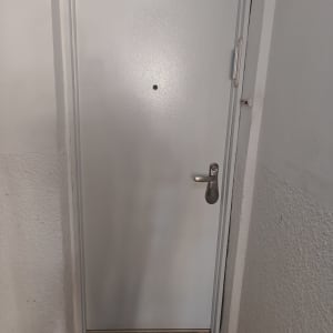 דלת לבנה עם ידית ומנעול, שטיחון ברוך הבא