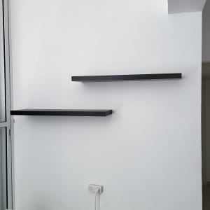 שתי מדפים שחורים מותקנים על קיר לבן