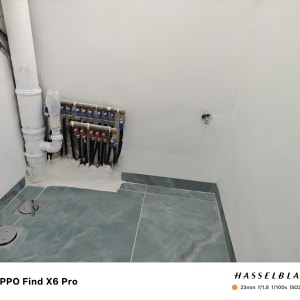 צנרת מים מותקנת על קיר עם אריחי רצפה חדשים