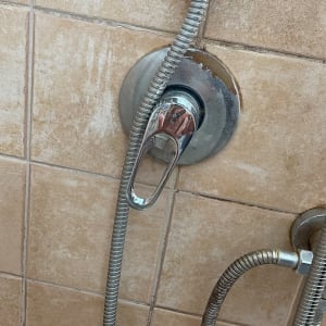 ברז מקלחת עם צינור מתכת על קיר אריחים