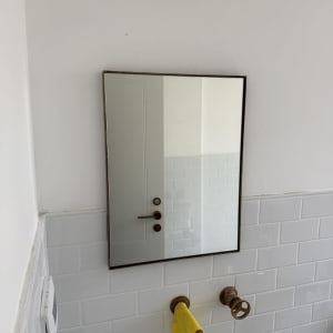 מראה וברזים בחדר אמבטיה עם מגבת צהובה