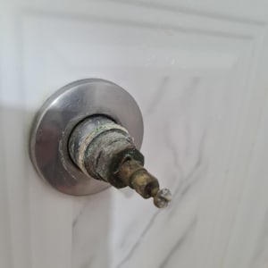 חיבור צינור מתכת עם חלודה על קיר קרמיקה