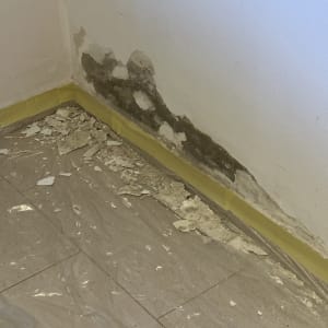 קיר עם טיח מתקלף ויריעות פלסטיק על הרצפה