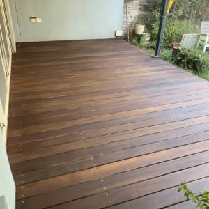 דק עץ חום מותקן בחצר עם צמחים מסביב