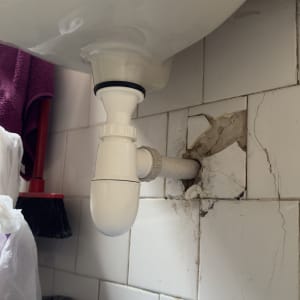 צינור ניקוז מתחת לכיור עם אריחים סדוקים