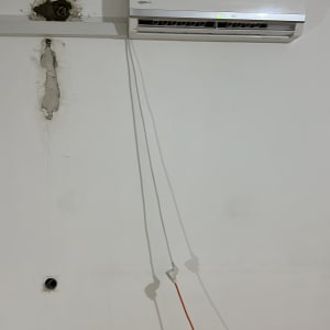 מזגן מותקן על קיר עם חוטי חשמל גלויים