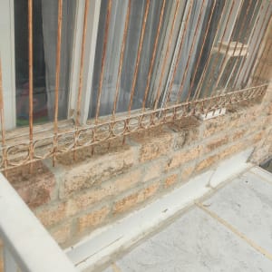 חלון עם סורגים על קיר אבן, איטום גג