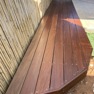 דק עץ חום ליד גדר במבוק בגינה