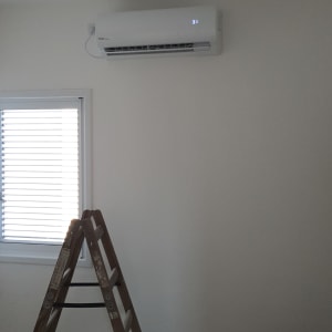 מזגן מותקן על קיר לבן עם תצוגה דיגיטלית