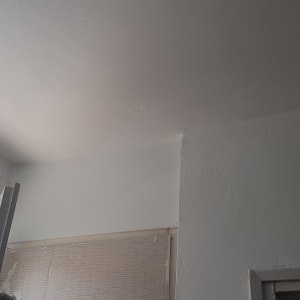 קיר ותקרה צבועים בלבן עם סימני תיקון