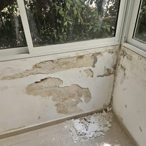 קיר מתקלף עם צבע מתקלף על הרצפה