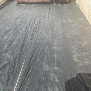 פריסת יריעת פלסטיק שחורה על הקרקע בגינה