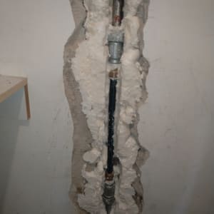 צינור מים מותקן בקיר עם חומר איטום סביבו