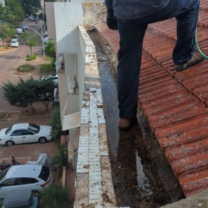 אדם עומד על גג עם צינור מים לניקוי