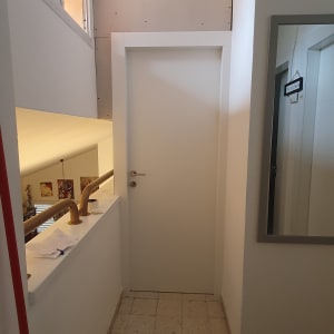 דלת לבנה במסדרון עם מעקה עץ