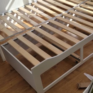 מסגרת מיטה מעץ עם שלבי עץ על רצפת עץ